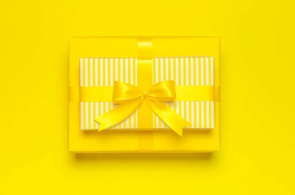 Appartamento sfondo vacanza laici. Due regalo giallo brillante regalo scatola con nastro e fiocco su sfondo giallo vista dall'alto copia spazio. Regalo di compleanno, 8 marzo, Festa della Mamma, San Valentino. Congratulazioni. — Foto Stock