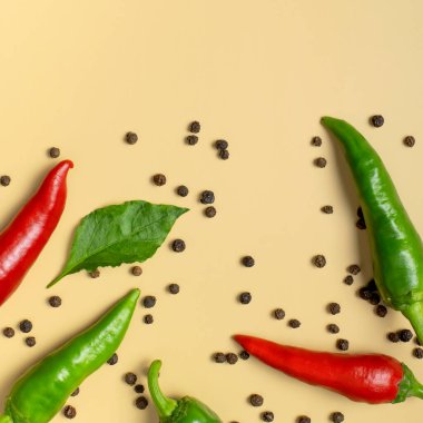 Sıcak kırmızı ve yeşil biberler, bej arka planda kuru siyah biberler düz manzarada yatıyordu. Yemek için baharat, yemek için baharat, acı biber, yemek. Yaratıcı düzen, kırmızı biber deseni