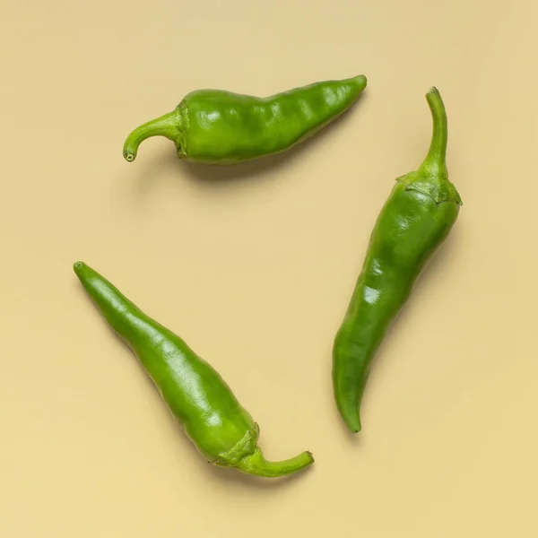 Warme groene verse chili pepers op beige achtergrond plat bovenaanzicht. Kruiden voor schotel, pittige specerijen om te koken, cayennepeper, voedsel. Creatieve lay-out, chili patroon — Stockfoto