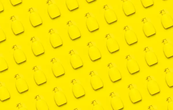 Жовтий пластиковий косметичний контейнер з дозатором на жовтому фоні плоский візерунок чистий контейнер без етикетки для мильного крему для лосьйону шампунь для ванни. Краса, спа, макети для брендингу — стокове фото
