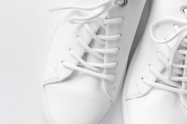 Beyaz arka planda beyaz kadın deri spor ayakkabıları düz yerde yatıyordu. Şık gençlik ayakkabıları, spor ayakkabıları, hakiki deri ayakkabılar. Minimalist ayakkabı mağazası reklamcılığı moda ayakkabısı arka planı.