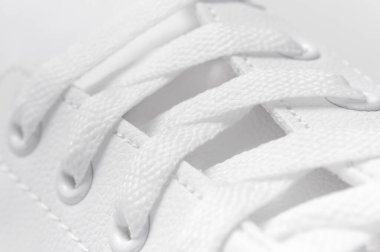 Beyaz kadın deri spor ayakkabıları, yakın çekim, makro fotoğraf. Şık gençlik ayakkabıları, spor ayakkabıları, hakiki deri ayakkabılar. Minimalist ayakkabı mağazası reklamı, moda, tarz. Ayakkabı arkaplanı.