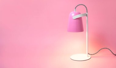Pembe arka plandaki modern masa lambası düzdü. Işık, lamba, ışık, iç dekorasyon, elektrik. Çocukların pembe masa lambası. Tek parça mobilya. Metal tasarımcı lamba.