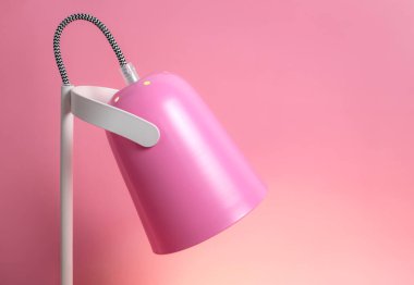Pembe arka plandaki modern masa lambası düzdü. Işık, lamba, ışık, iç dekorasyon, elektrik. Çocukların pembe masa lambası. Tek parça mobilya. Metal tasarımcı lamba.