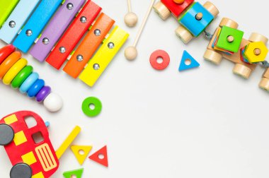 Beyaz arka planda doğal ahşaptan yapılmış çocuk oyuncakları. Çok renkli piramit, tren, inşaatçı, gökkuşağı renklerinde ksilofon. Eko dostu oyuncak, plastiksiz. Bebekler ve yeni yürümeye başlayanlar için oyuncaklar.