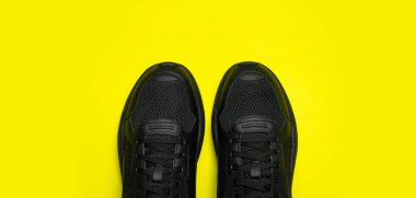 Parlak sarı arka planda siyah klasik erkek ayakkabıları. Modaya uygun gençlik spor ayakkabıları. Spor ayakkabıları. Spor ayakkabısı, koşu, sağlıklı yaşam tarzı. Düz görünüm kopyalama alanı.