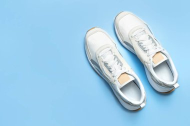 Mavi arka planda bir çift açık renk erkek ayakkabısı. Spor ayakkabıları, spor ayakkabıları, spor ayakkabıları, koşu, antrenman. Spor ayakkabılarla minimalist bir geçmişi var. Sağlıklı yaşam tarzı kavramı. Düz görünüm kopyalama alanı.