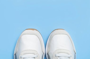 Mavi arka planda bir çift açık renk erkek ayakkabısı. Spor ayakkabıları, spor ayakkabıları, spor ayakkabıları, koşu, antrenman. Spor ayakkabılarla minimalist bir geçmişi var. Sağlıklı yaşam tarzı kavramı. Düz görünüm kopyalama alanı.