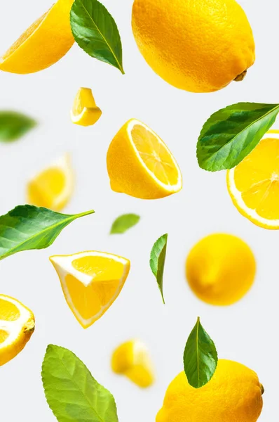 Сочные Спелые Летящие Желтые Лимоны Зеленые Листья Светло Сером Фоне — стоковое фото