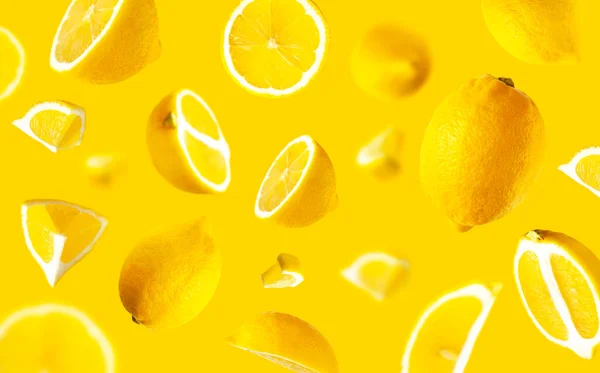 Juicy ripe flying lemons on yellow background. Creative food concept. Tropical organic fruit, citrus, vitamin C. Lemon whole and sliced. Summer minimalistic bright fruit background. Lemon pattern.