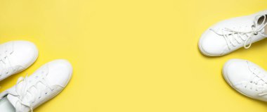 Sarı arka planda beyaz spor ayakkabılar düz yerde yatıyordu. Şık genç kadın deri ayakkabıları, spor ayakkabıları, hakiki deri ayakkabılar. Minimalist ayakkabı mağazası reklamcılığı moda ayakkabısı arka planı.