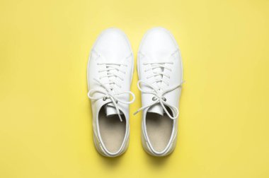 Sarı arka planda beyaz spor ayakkabılar düz yerde yatıyordu. Şık genç kadın deri ayakkabıları, spor ayakkabıları, hakiki deri ayakkabılar. Minimalist ayakkabı mağazası reklamcılığı moda ayakkabısı arka planı.