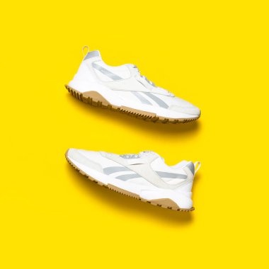 Sarı arka planda bir çift hafif erkek ayakkabısı. Spor ayakkabıları, spor ayakkabıları, spor ayakkabıları, koşu, antrenman. Spor ayakkabılarla minimalist bir geçmişi var. Sağlıklı yaşam tarzı konsepti Düz görünüm kopya alanı yatıyordu.