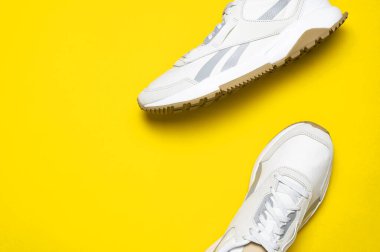 Sarı arka planda bir çift hafif erkek ayakkabısı. Spor ayakkabıları, spor ayakkabıları, spor ayakkabıları, koşu, antrenman. Spor ayakkabılarla minimalist bir geçmişi var. Sağlıklı yaşam tarzı konsepti Düz görünüm kopya alanı yatıyordu.