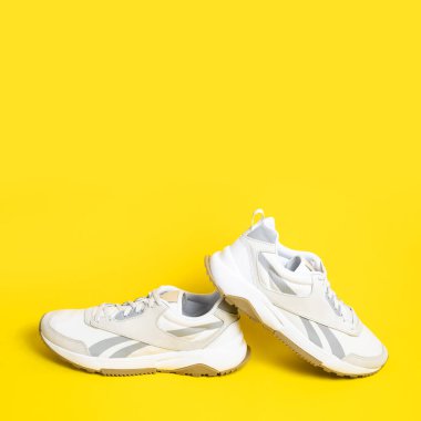 Sarı arka planda bir çift hafif erkek ayakkabısı. Spor ayakkabıları, spor ayakkabıları, spor ayakkabıları, koşu, antrenman. Spor ayakkabılarla minimalist bir geçmişi var. Sağlıklı yaşam tarzı konsepti Düz kopya alanı.