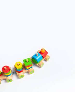 Beyaz zemin üzerinde renkli bloklar olan ahşap tren. Gökkuşağı renginde doğal ahşaptan yapılmış çocuk oyuncakları. Eko dostu oyuncak, oyun, plastiksiz. Bebekler ve yeni yürümeye başlayanlar için oyuncak. Düz üst görünüm.