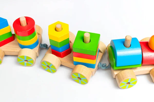 Wooden train with colored blocks on white background. Kids toys made of natural wood in rainbow colors. Eco friendly toy, game, plastic free. Toy for babies and toddlers. Flat lay side view.