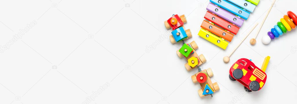 Children's toys made of natural wood on white background. Multi-colored pyramid, train, xylophone in rainbow colors. Eco friendly toy, plastic free. Toy for babies and toddlers. Flat lay top view.