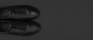 Siyah arka planda siyah deri erkek ayakkabıları. Modaya uygun gençlik spor ayakkabıları. Spor ayakkabıları düz görünüm fotokopi alanı yatıyordu. Spor ayakkabısı, koşu, sağlıklı yaşam tarzı..