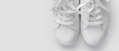 Beyaz arka planda beyaz kadın deri spor ayakkabıları düz yerde yatıyordu. Şık gençlik ayakkabıları, spor ayakkabıları, hakiki deri ayakkabılar. Minimalist ayakkabı mağazası reklamcılığı moda ayakkabısı arka planı.