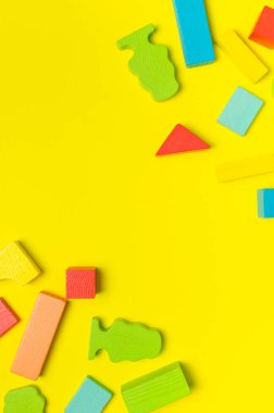 Parlak sarı zemin üzerinde doğal ahşaptan yapılmış çok renkli çocuk müteahhidi üst tarafta yatıyordu. İnşaat için renkli çocuk tuğlaları. Bina blokları arka plan. Oyuncak geliştirme, oyun.