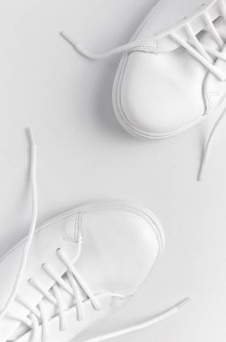 Beyaz arka planda beyaz kadın deri spor ayakkabıları düz yerde yatıyordu. Şık gençlik ayakkabıları, spor ayakkabıları, hakiki deri ayakkabılar. Minimalist ayakkabı mağazası reklamcılığı moda ayakkabısı arka planı.