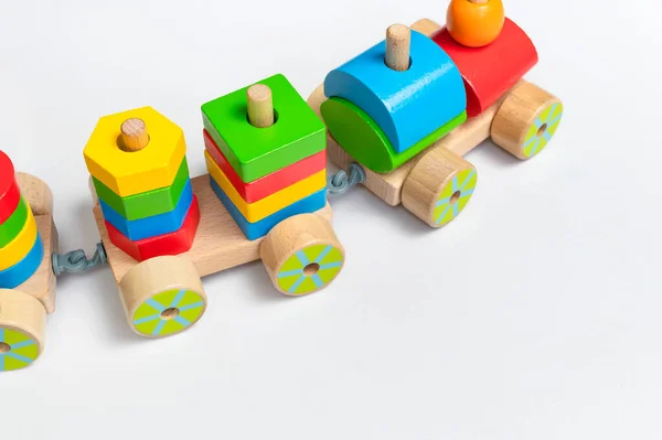 Wooden train with colored blocks on white background. Kids toys made of natural wood in rainbow colors. Eco friendly toy, game, plastic free. Toy for babies and toddlers. Flat lay.