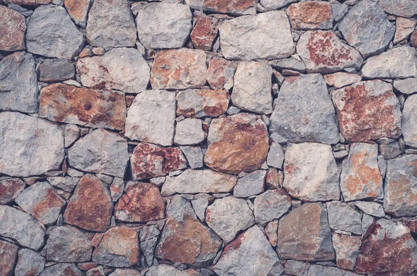 Modern wall of large unprocessed pieces of rock, stones. Background stone wall.