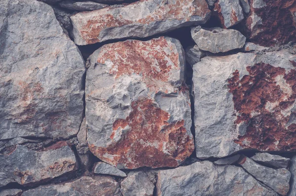 Modern wall of large unprocessed pieces of rock, stones. Background stone wall.