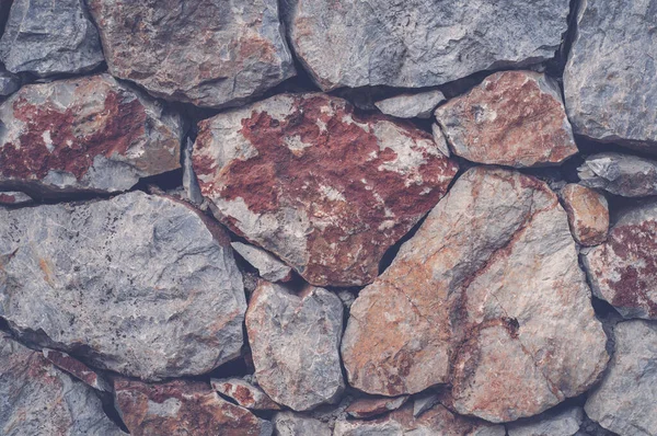 Modern wall of large unprocessed pieces of rock, stones. Background stone wall.