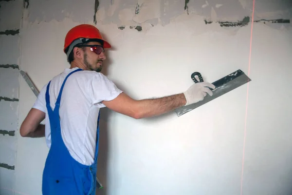 builder worker plastering facade of high-rise building with putty knife