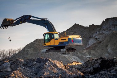 Mavi gökyüzüne karşı bir inşaat alanında sarı kazıcı