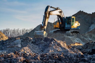 Mavi gökyüzüne karşı bir inşaat alanında sarı kazıcı