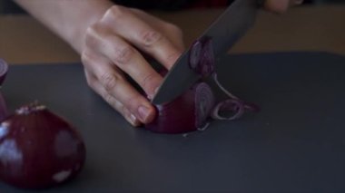 Yüzü olmayan kişi kırmızı soğan kesiyor.