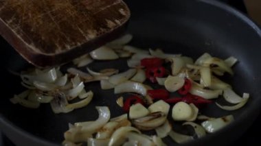 Tavada kızarmış soğan ve spatulayla karıştırılmış sarımsak ve kırmızı biber.