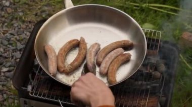 Kömür ızgarasında sosis çeviren hasatçı. 