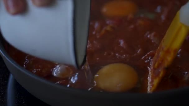 Cook tillsätta råa ägg till kokande kryddig sås i stekpanna — Stockvideo