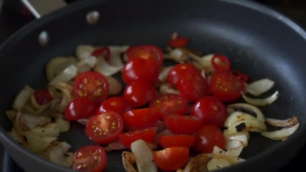 Adding halved cherry tomatoes to frying vegetables on pan — Stock Video