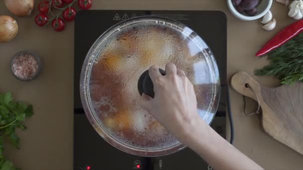 Повар открывает туманную крышку кастрюли с кипящим томатным соусом с яйцами — стоковое видео