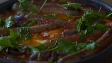 Kızartma tavasında maydanoz ve kırmızı biber ile kaynatılmış Shakshuka tabağı.