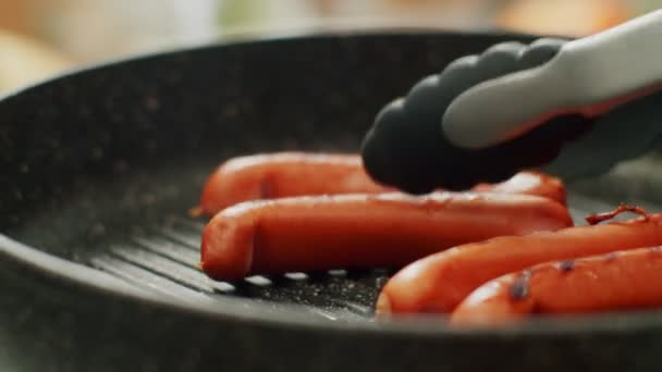 Szef kuchni gotuje kiełbaski na patelni grilla — Wideo stockowe