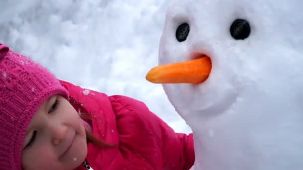 Liten flicka skulpterar snögubbe utomhus — Stockvideo