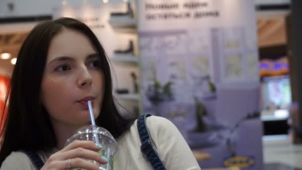 Young beautiful girl is drinking a mojito on the food court — Stock Video