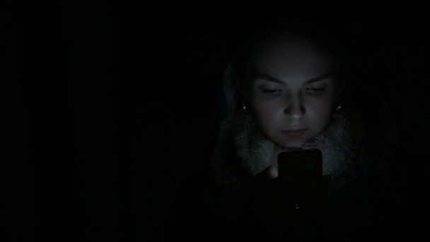 Jonge vrouw maakt gebruik van een smartphone's nachts — Stockvideo