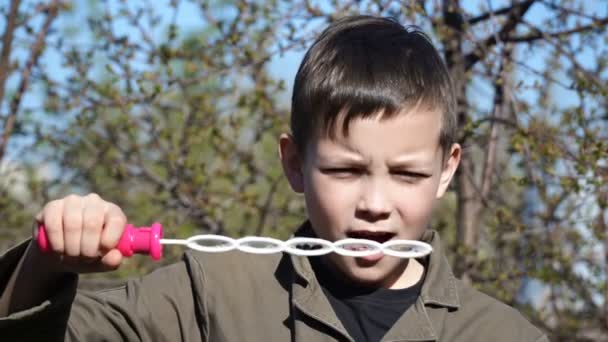 Beeldmateriaal jongen blowing bubbles buitenshuis. — Stockvideo