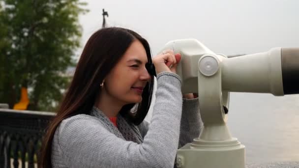 Chica mira a través de prismáticos en el paseo marítimo — Vídeo de stock