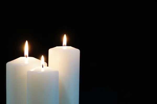 Burning candles isolated on black background. Stock Photo