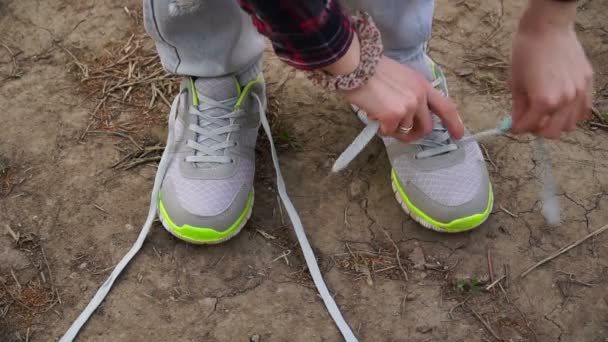 Young girl commits an outdoor walk and stopped to tie his shoelaces on sneakers — Stock Video