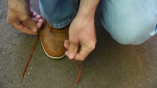 Männer gehen im Freien spazieren und schnüren seine Schnürsenkel an Turnschuhen. — Stockvideo