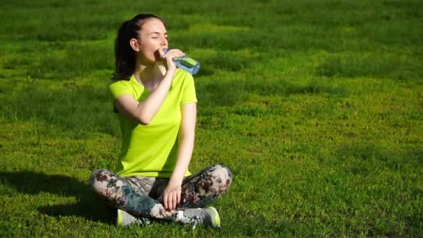 Laufende Frau hielt an, um im Park Wasser zu trinken. Fitness Mädchen Training im Freien — Stockvideo